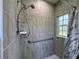 Updated shower featuring tiled walls, adjustable shower head, grab bar, and a bright window at 1136 Granada St, Clearwater, FL 33755