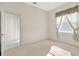 Bedroom featuring neutral colored walls, a window and doorway to the bathroom in this carpeted room at 11908 Pilot Country Dr, Spring Hill, FL 34610