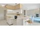 Well-lit kitchen featuring bar-style seating and white appliances and cabinets at 11908 Pilot Country Dr, Spring Hill, FL 34610