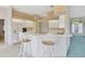 Bright kitchen with white cabinets and bar-style seating adjacent to the living room at 11908 Pilot Country Dr, Spring Hill, FL 34610
