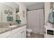 Stylish bathroom features a granite countertop vanity, tiled floors, and a shower with a polka dot curtain at 12138 Criollo Rd, Spring Hill, FL 34610