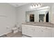 Well-lit bathroom with granite counters, a white vanity, a toilet, and a large mirror over the sink at 12138 Criollo Rd, Spring Hill, FL 34610