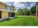 Spacious grassy backyard with mature trees, screened lanai, and easy access to enjoy the serene outdoor space at 1241 Redondo Way, Wesley Chapel, FL 33543