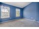 A bedroom with blue walls, carpet flooring, and two windows with blinds and valances at 1241 Redondo Way, Wesley Chapel, FL 33543