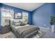 Bedroom features cozy bed with nightstands and lamps, large windows, and blue walls at 1241 Redondo Way, Wesley Chapel, FL 33543