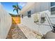 Side yard showing the white exterior, a wooden gate and privacy fence at 1320 Dixie S Ln, St Petersburg, FL 33707