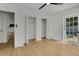 Bedroom features light wood floors, neutral paint, a closet, an exterior door and a view of a pool at 1320 Dixie S Ln, St Petersburg, FL 33707