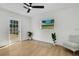 Bedroom features a ceiling fan, light wood floors, neutral paint, a window, an exterior door and a chair at 1320 Dixie S Ln, St Petersburg, FL 33707