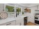 Bright kitchen with farmhouse sink, gooseneck faucet, stainless steel appliances, and wooden shelving at 1320 Dixie S Ln, St Petersburg, FL 33707