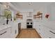 Modern kitchen with white cabinets, stainless steel appliances, open shelving, and stylish backsplash at 1320 Dixie S Ln, St Petersburg, FL 33707