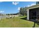 A spacious backyard featuring a green lawn, white fence, screened porch, and inviting fire pit area at 13252 Graham Yarden Dr, Riverview, FL 33579