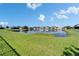Scenic pond view with lush green grass, blue sky, and neighborhood homes in the background at 13252 Graham Yarden Dr, Riverview, FL 33579