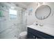 Modern bathroom features a glass shower with marble look tile and a vanity with round mirror at 1712 Azalea Ct # A, Oldsmar, FL 34677