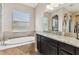 Elegant bathroom with a soaking tub, granite vanity, and a large arched mirror at 17914 Howsmoor Pl, Lutz, FL 33559