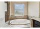 A luxurious soaking tub is featured beneath a bright window, paired with a tiled shower in this stylish bathroom at 17914 Howsmoor Pl, Lutz, FL 33559