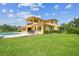 Exterior shot of the sprawling home with a large pool, well-manicured lawn, and a second story balcony at 17914 Howsmoor Pl, Lutz, FL 33559