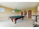 Bright game room featuring a pool table and arched doorways leading to a carpeted staircase at 17914 Howsmoor Pl, Lutz, FL 33559