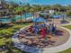 Aerial view of a colorful playground with slides, climbing structures, and shaded seating areas at 17914 Howsmoor Pl, Lutz, FL 33559