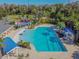 Aerial view of a large rectangular pool with shaded seating areas surrounded by lush landscaping and playground at 17914 Howsmoor Pl, Lutz, FL 33559