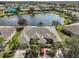 Aerial view of a well-maintained residential area with a lake, mature trees, and a red car parked in the driveway at 2239 Sifield Greens Way # 84, Sun City Center, FL 33573