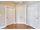 Hallway with three white doors and hardwood floors at 23320 Dinhurst Ct, Land O Lakes, FL 34639