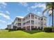 Low-angle exterior of condo building featuring large lawn, screened lanais and lush landscaping at 2725 Terra Ceia Bay Blvd # 104, Palmetto, FL 34221