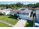 Aerial view of a well-maintained two-story home with a front balcony, green lawn, and mature trees at 2897 Rosery Ne Rd, Largo, FL 33771