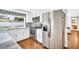 Stainless steel fridge and range in a kitchen with white cabinetry, mosaic backsplash, and hardwood flooring at 2897 Rosery Ne Rd, Largo, FL 33771