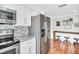 Bright kitchen with stainless appliances, white cabinets, modern mosaic backsplash, and hardwood floors at 2897 Rosery Ne Rd, Largo, FL 33771