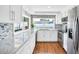 Galley kitchen featuring white cabinets, stainless steel appliances, and a sunny window at 2897 Rosery Ne Rd, Largo, FL 33771