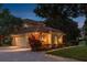 Exterior dusk shot showcases the home, brick driveway, landscaping and three car garage at 3042 Wentworth Way, Tarpon Springs, FL 34688