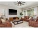 Cozy living room featuring leather furniture, large windows, and a modern ceiling fan at 3042 Wentworth Way, Tarpon Springs, FL 34688