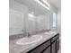 Elegant bathroom vanity with dual sinks, granite countertops, and stylish lighting fixtures above a large mirror at 30732 Summer Sun Loop, Wesley Chapel, FL 33545