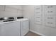 Bright laundry room featuring a white washer and dryer, a wire shelf, and utility panels on the wall at 30732 Summer Sun Loop, Wesley Chapel, FL 33545