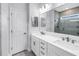 Bathroom featuring a double vanity with sleek hardware, large mirrors, and a glass-enclosed shower at 3807 W Cleveland St, Tampa, FL 33609