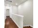 Second floor hallway with hardwood floors, a white banister, neutral walls, and doorways leading to other rooms at 3807 W Cleveland St, Tampa, FL 33609