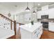 Open-concept kitchen with stainless steel appliances and wood flooring, adjacent to stairs at 3807 W Cleveland St, Tampa, FL 33609