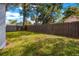 Fenced backyard with lush green grass and mature trees, perfect for outdoor activities at 403 E North St, Tampa, FL 33604
