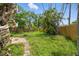 Overgrown backyard featuring green grass, trees, tropical foliage, and a wooden fence at 4101 Shore Acres Ne Blvd, St Petersburg, FL 33703