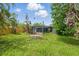Backyard featuring green grass and tropical foliage with fence and screened in lanai at 4101 Shore Acres Ne Blvd, St Petersburg, FL 33703