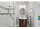 Updated bathroom featuring a glass shower with decorative tile accents, vanity, and a stylish round mirror at 4615 Shark Dr, Bradenton, FL 34208