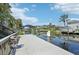 Scenic waterfront view featuring a well-maintained dock, lush landscaping, and clear blue skies at 4615 Shark Dr, Bradenton, FL 34208