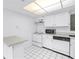 Kitchen with an island, white appliances, and tiled flooring under a drop ceiling at 500 N Osceola Ave # 211, Clearwater, FL 33755