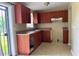 A functional kitchen equipped with wood cabinetry, tile flooring, and natural light from windows and door at 5016 S 86Th St, Tampa, FL 33619