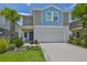 Charming two-story home with a well-manicured lawn, palm trees, and a two-car garage at 5438 Summer Sunset Dr, Apollo Beach, FL 33572