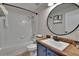 Cozy bathroom featuring a blue vanity with wood countertop, round mirror, and tiled shower/tub combo at 5918 Beaconpark St, Lithia, FL 33547