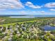 Aerial view of a community featuring homes, lush greenery, and a scenic lake in the background at 602 Timber Bay W Cir, Oldsmar, FL 34677