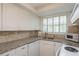 Bright kitchen with granite countertops, stainless steel sink, brick backsplash and plenty of white cabinets at 6658 Stewart N Ave, St Petersburg, FL 33702