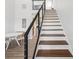 Hardwood staircase with white risers and modern railings leading to the kitchen and dining area at 6707 Wander Ln, New Port Richey, FL 34654