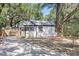 Side view of a white single-story house showcasing its exterior features, framed by mature trees and a long driveway at 6806 N 17Th St, Tampa, FL 33610